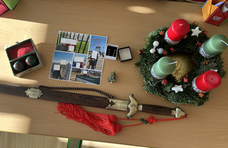 Ein Tisch mit versch. Gegenständen: Adventkranz, Schwert, Brosche, Urlaubsfoto, Qi Gong Kugeln. 