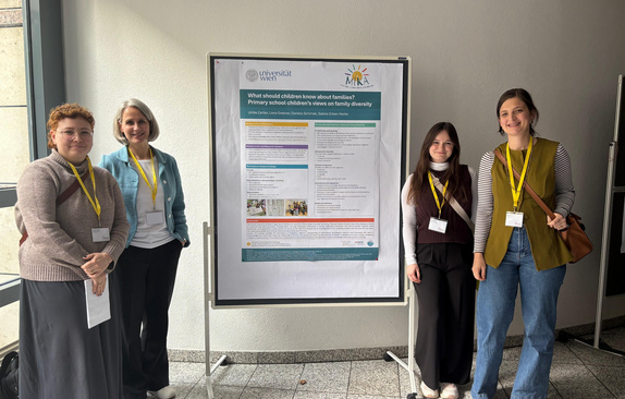 Vier Personen aus dem Team (Daniela, Ulrike, Lena und Sabine) stehen neben einem aufgehängten Plakat bei der FACES Konferenz in München